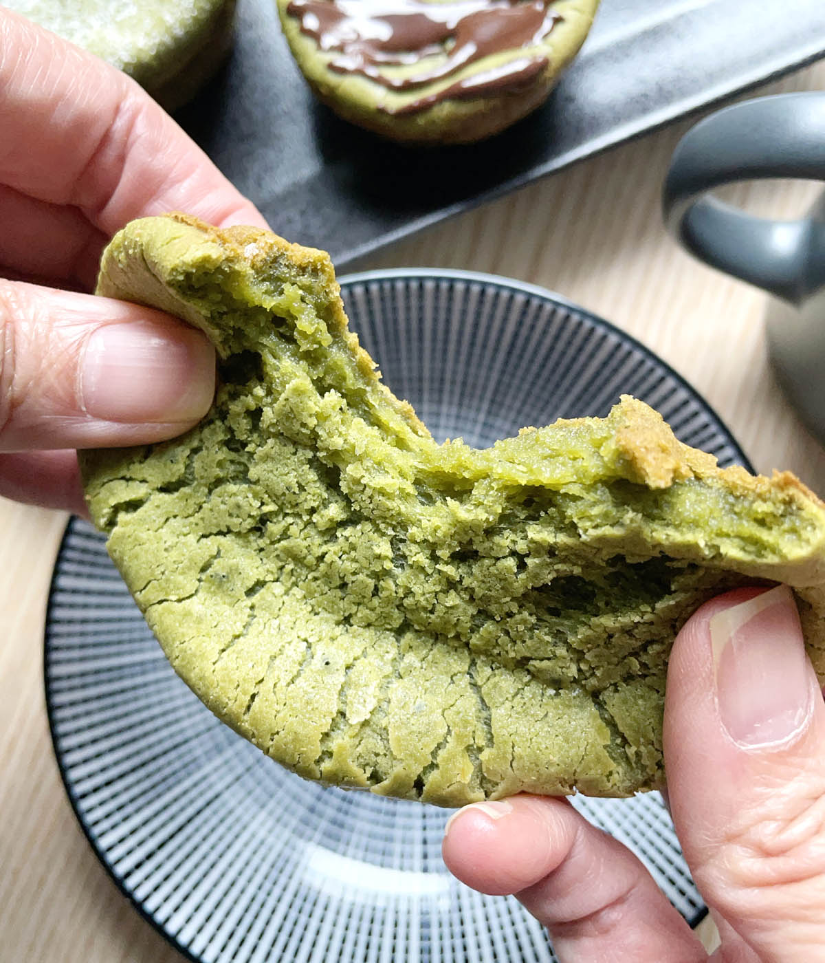 Close-up of two hands pulling apart a green muffin.