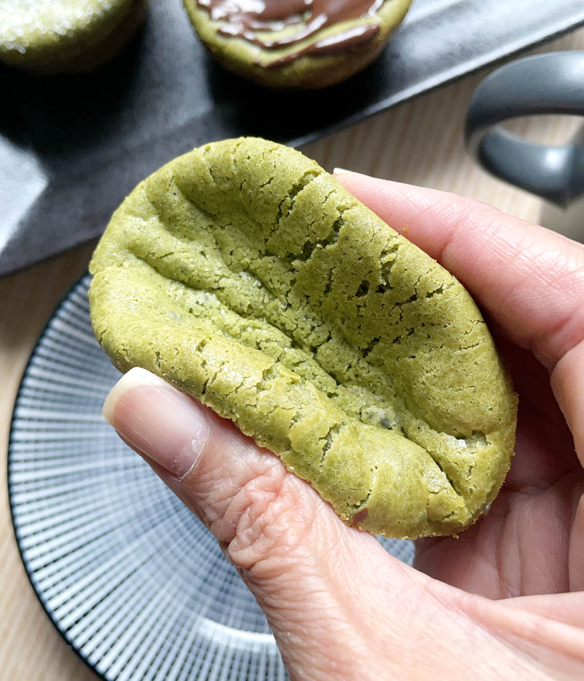 Close-up of a hand squeezing a green matcha mochi muffin.