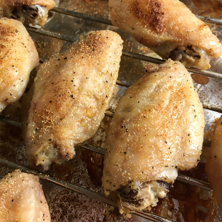 Close-up of brown baked chicken wings on a metal rack on a pan