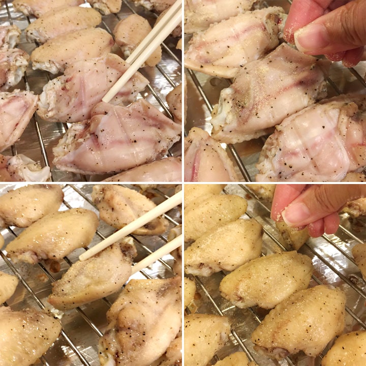 Chicken wings being flipped over on a baking rack with chopsticks and seasoned with a yellow powder