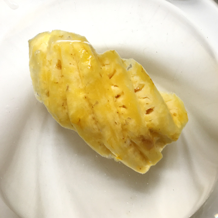 A chunk of yellow pineapple in a bowl of water