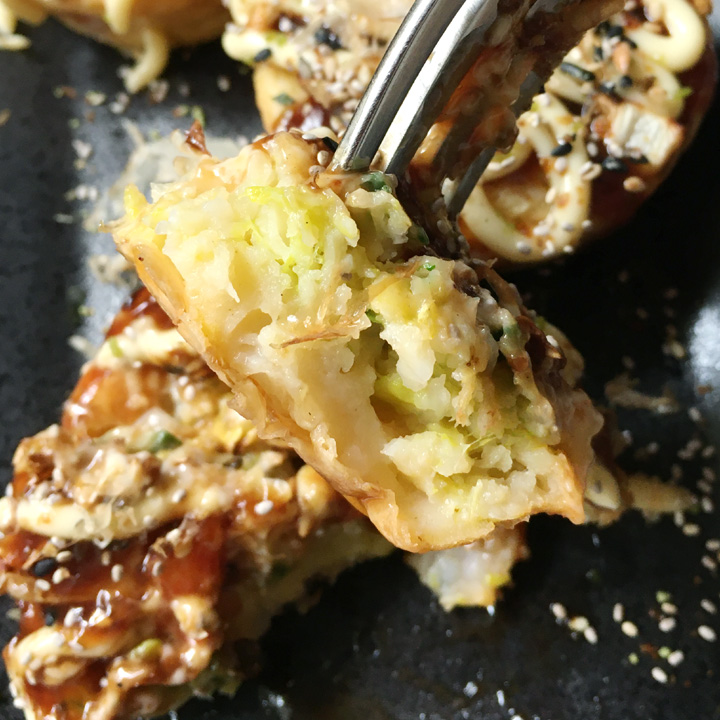 Close-up of a fork holding a piece of an okonomiyaki bite