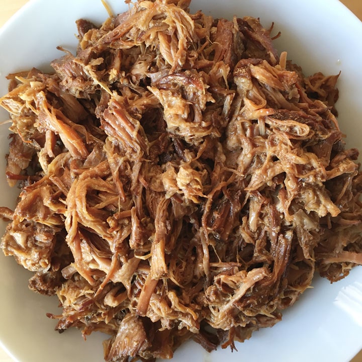 A white bowl containing pulled pork.