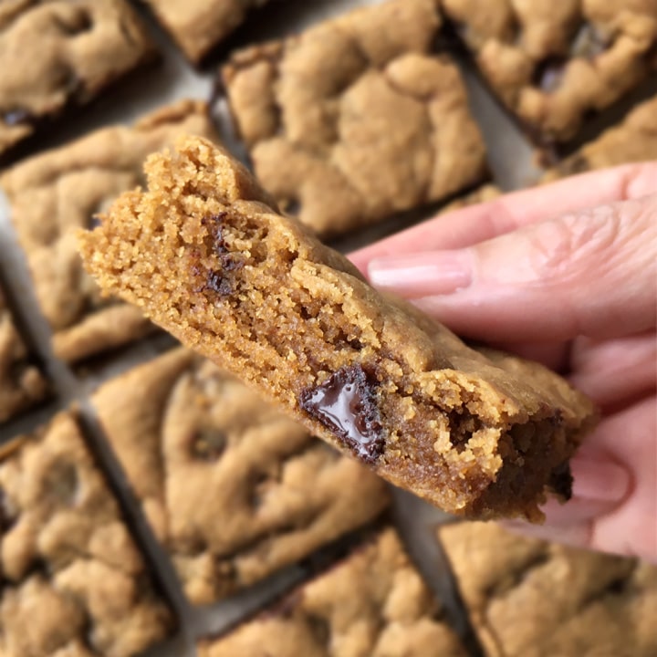Close-up of the edge of a cookie bar being held by a hand.