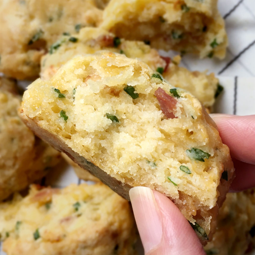 Close-up of a hand holding a Bacon Cheddar Scallion Scone.