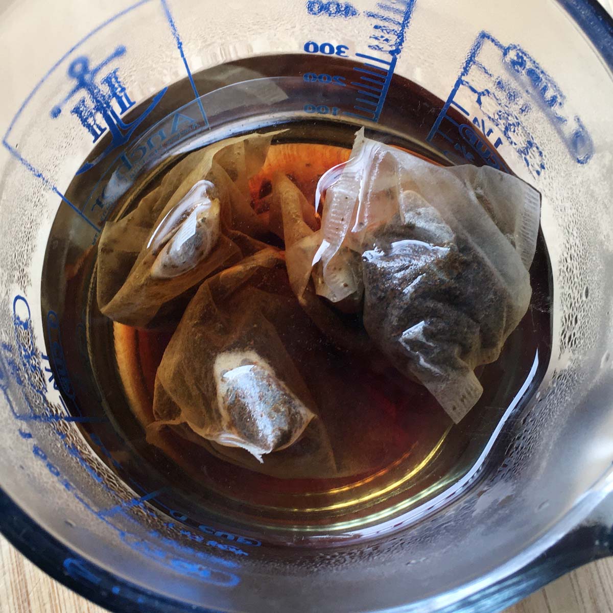 Tea bags sitting in water in a measuring cup.
