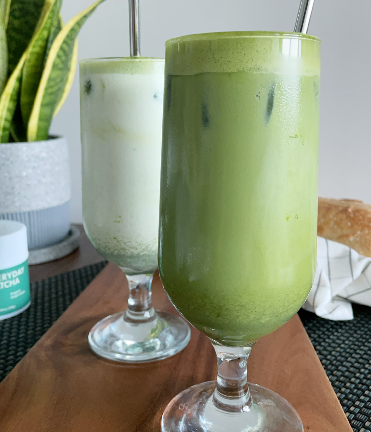 Two drinking glasses, one containing a white liquid, one containing a green liquid.