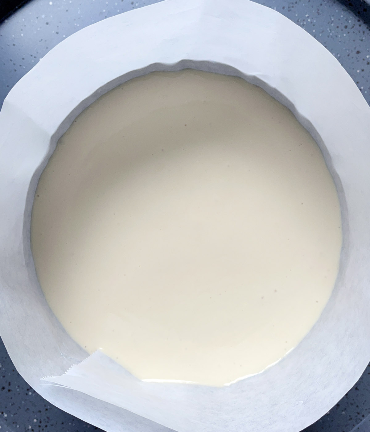 White batter in a paper lined round pan.