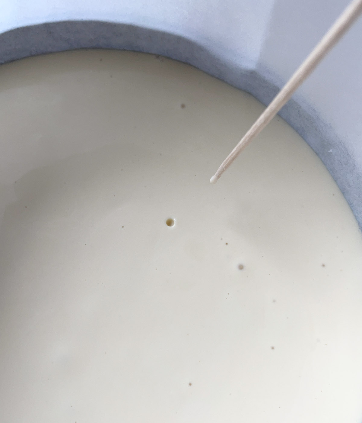 Close-up of a toothpick popping an air bubble in cake batter.