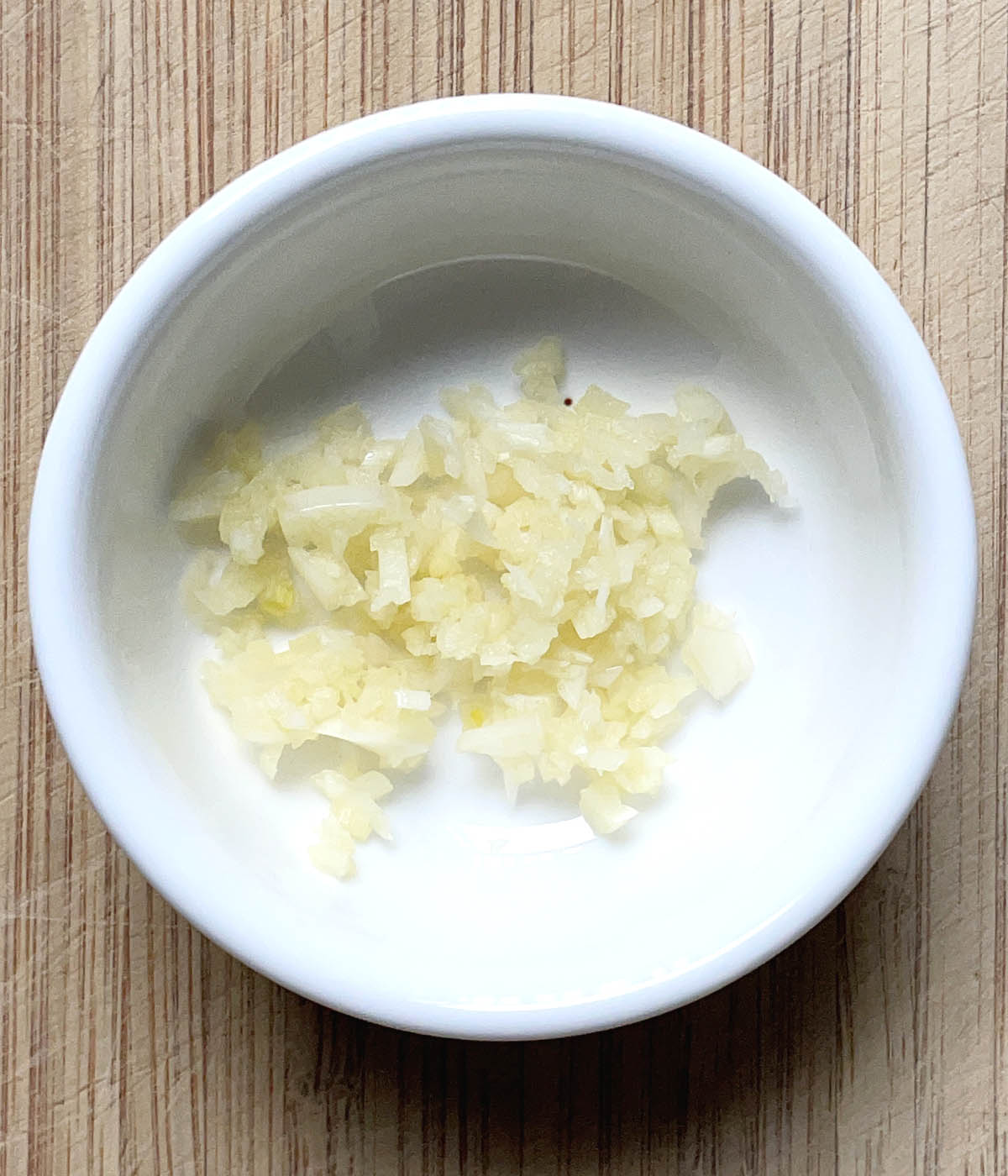 Minced garlic in a round white dish.