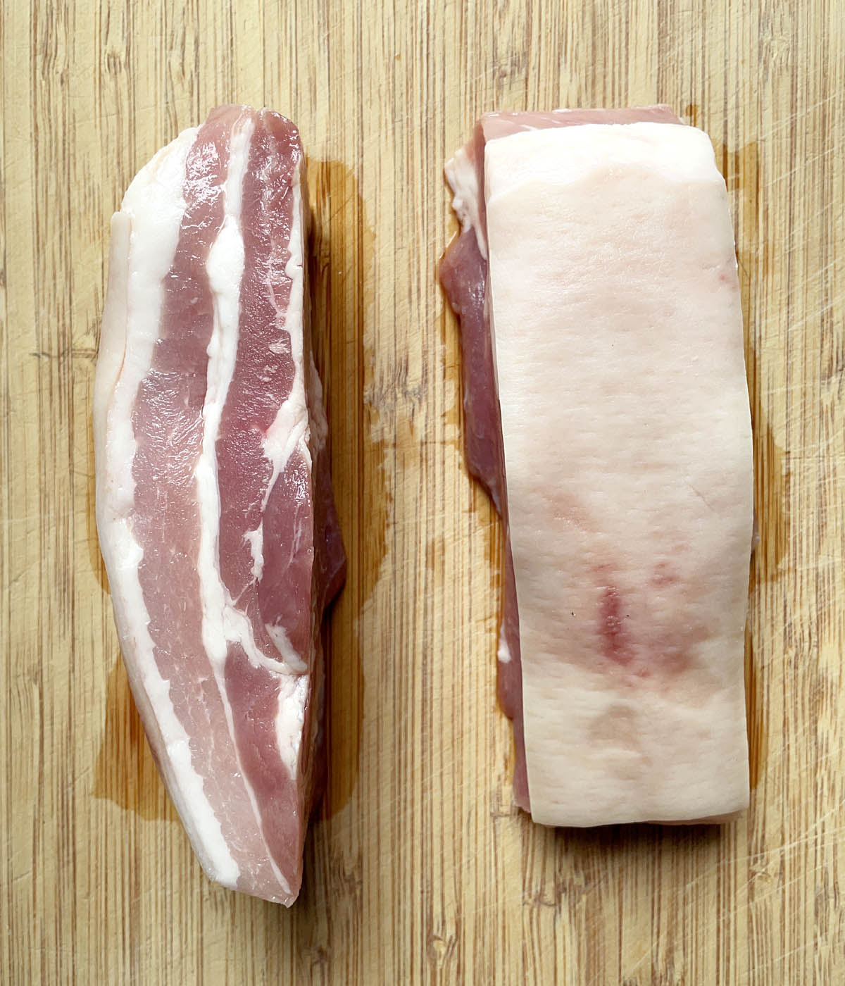 Two pieces of raw pork belly, one piece on its side.