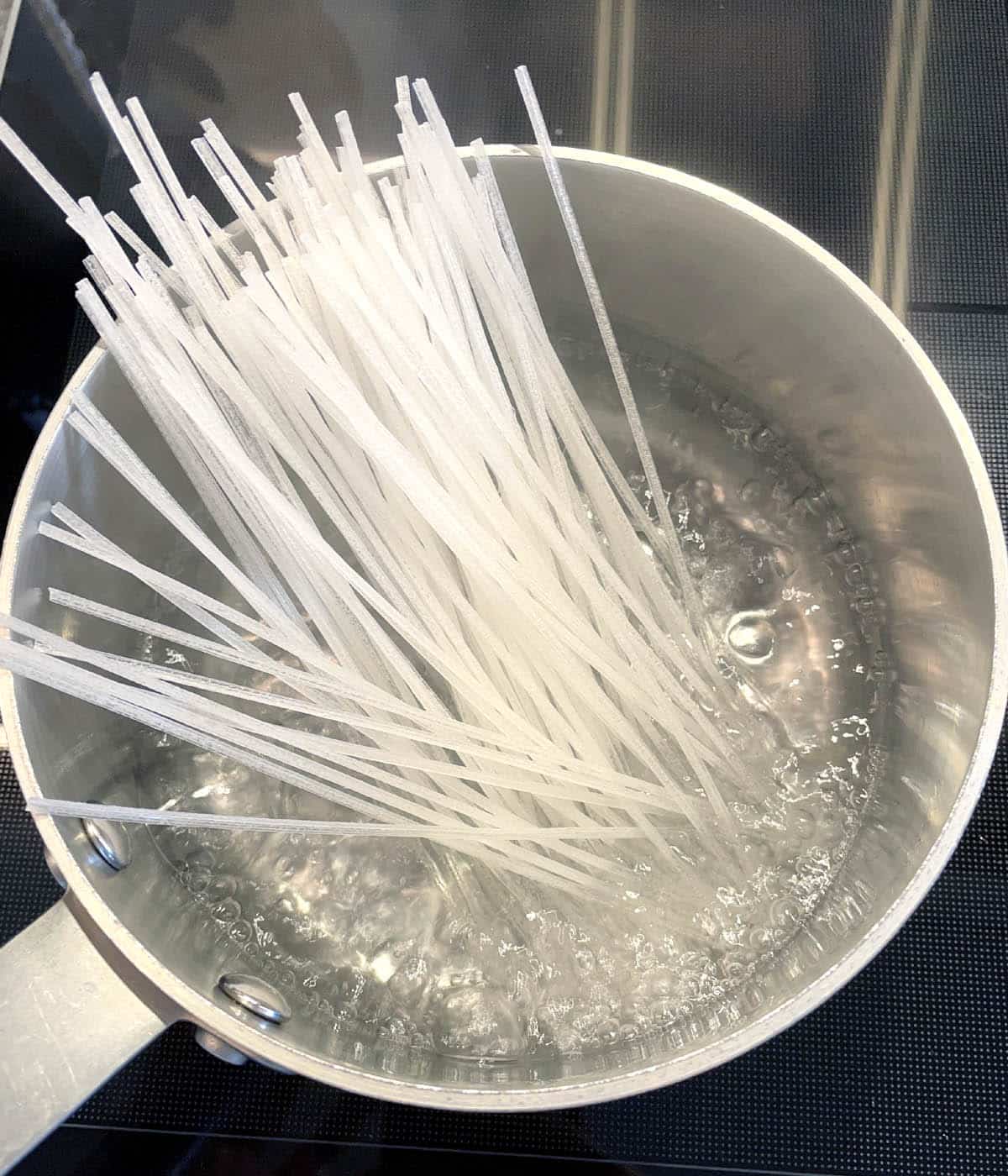 White noodle sticks in a pot of boiling water.