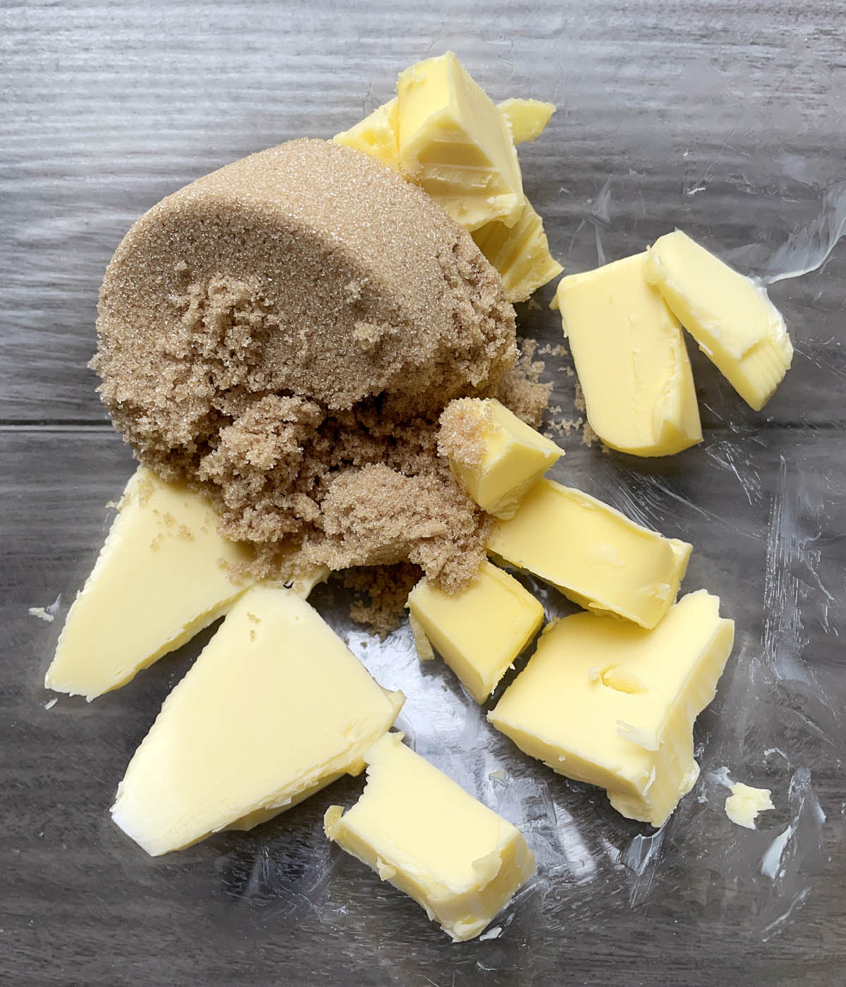 A glass bowl containing brown sugar and yellow butter chunks.