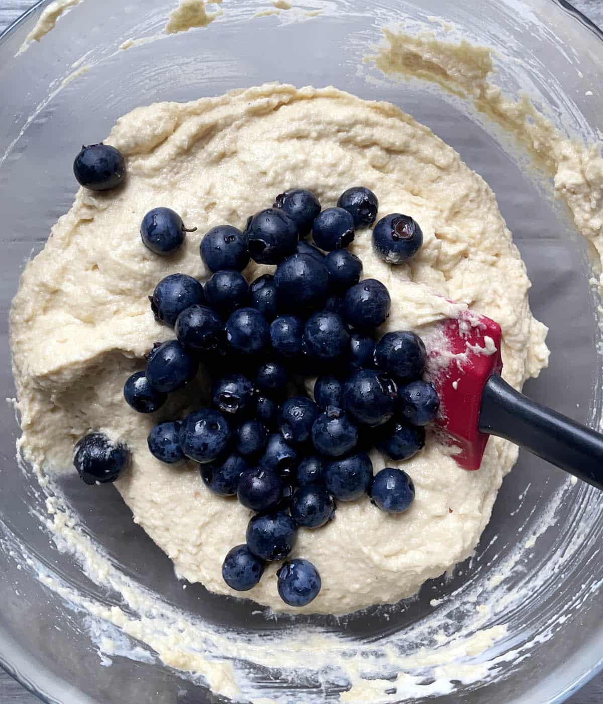Blueberries and light brown batter in a bowl.