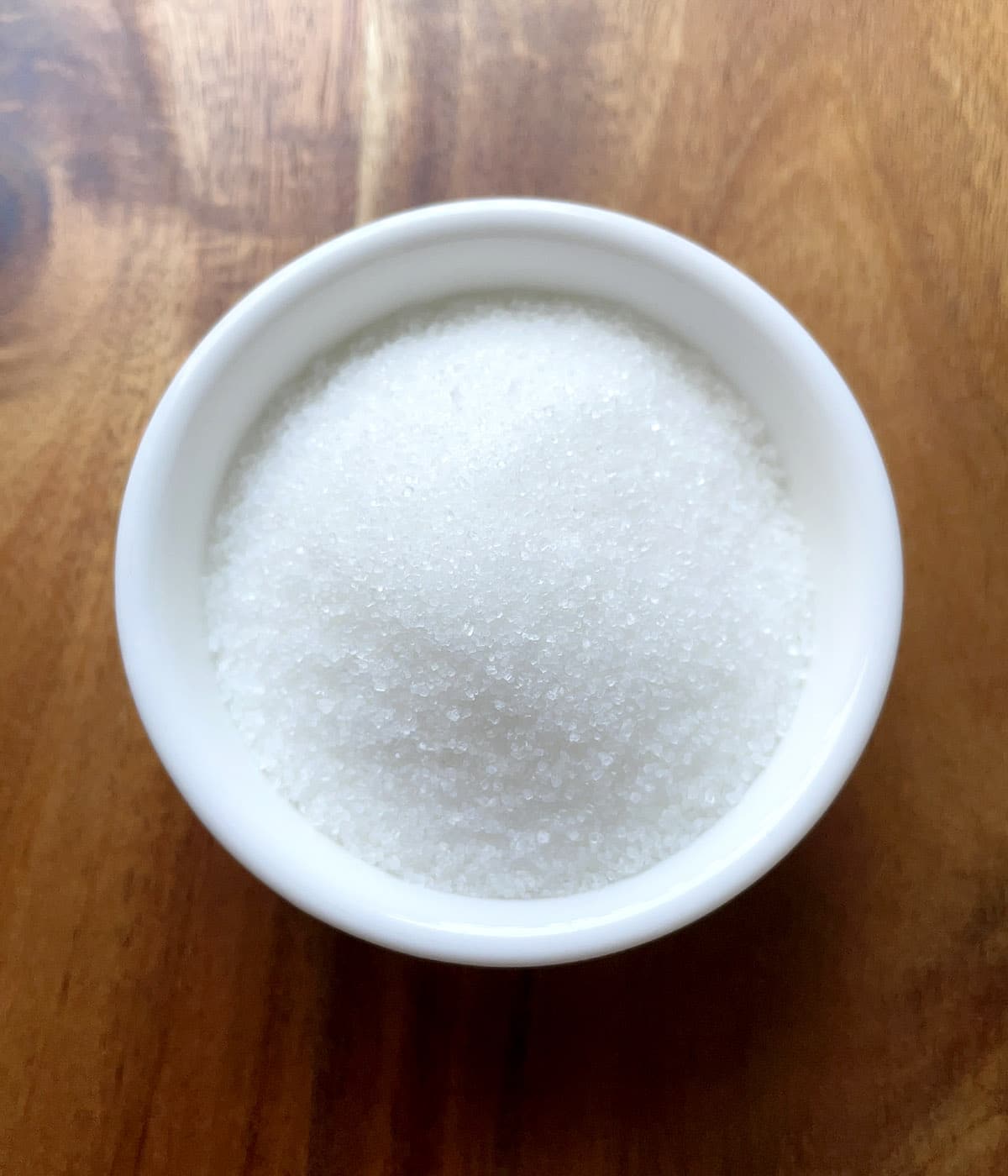 A round white dish containing white sugar.