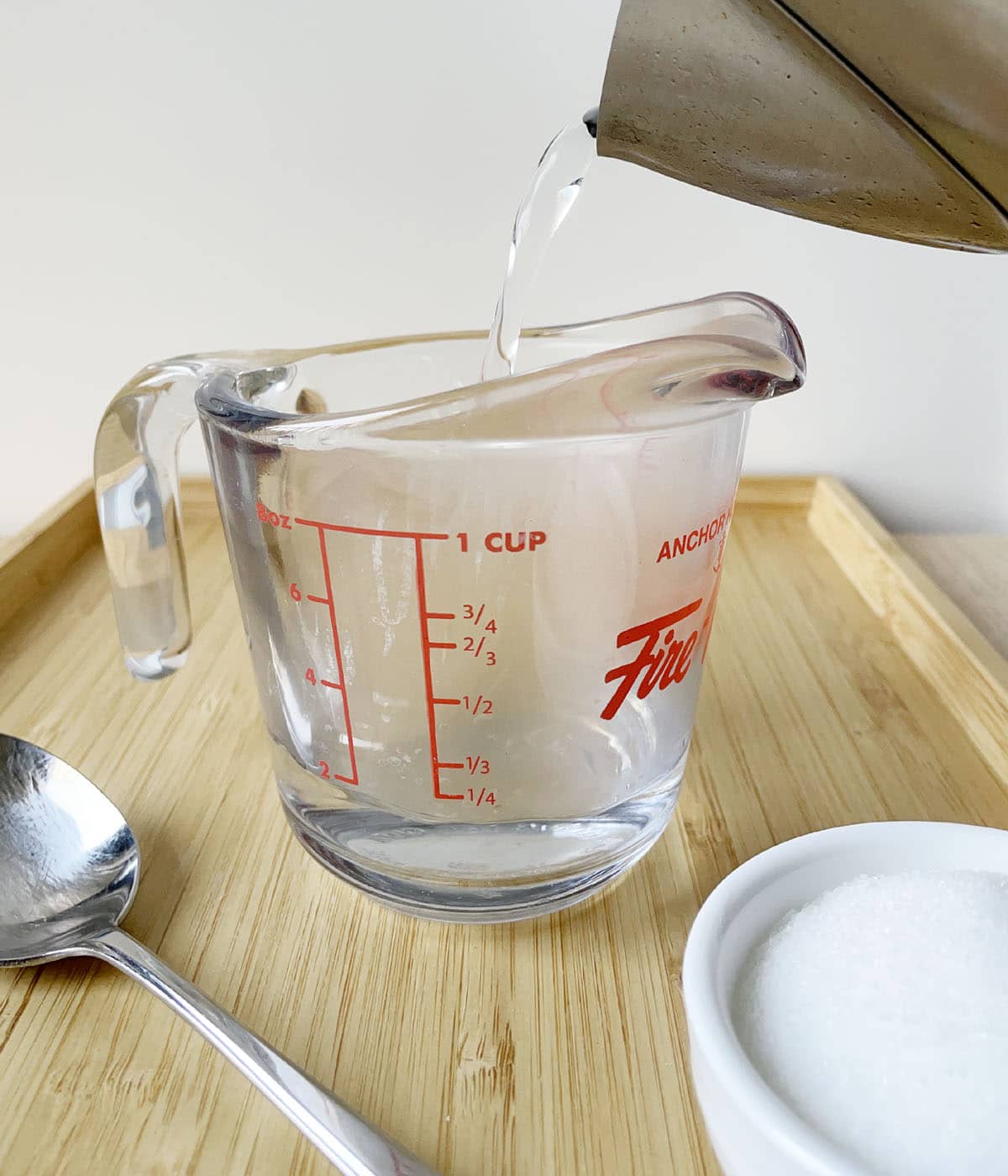 Hot water being poured from a kettle into a glass measuring cup.