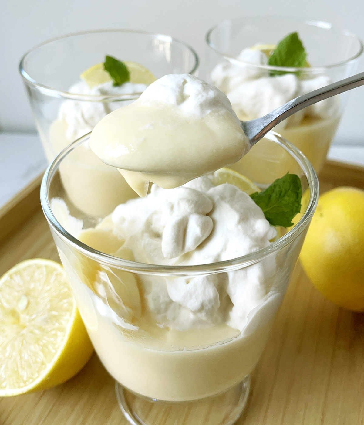 Close-up of a spoonful of lemon pudding and whipped cream over a glass dish.