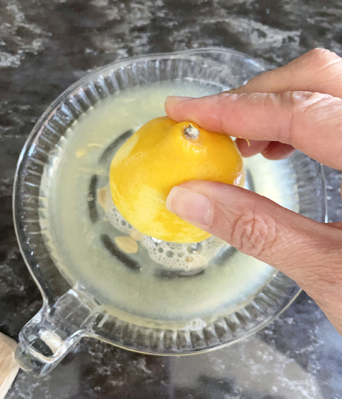 A hand juicing half a lemon.