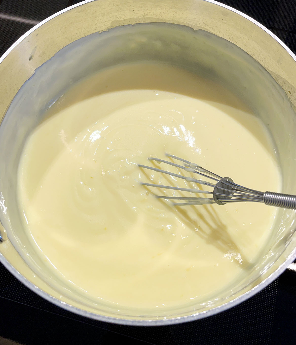 A whisk in a pot of lemon pudding.