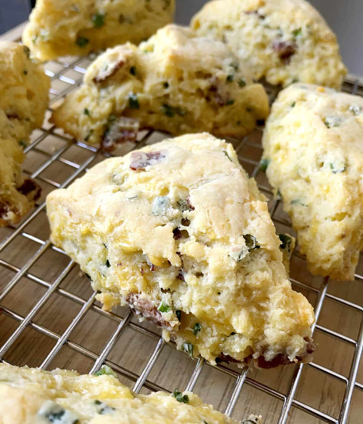 Close-up of a bacon cheddar scallion scone on a metal rack.